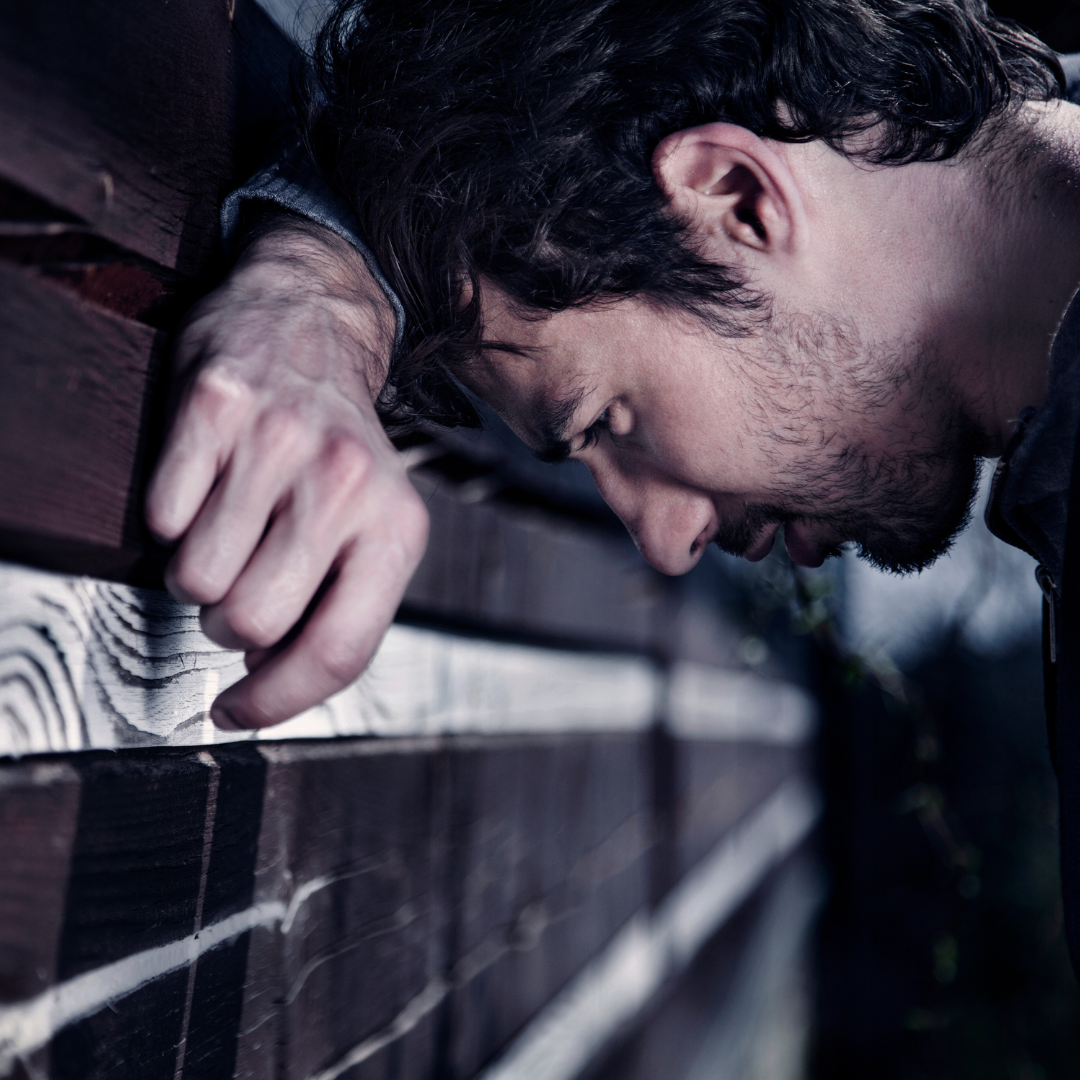 Gay man leaning against a wall, showing emotional pain and isolation