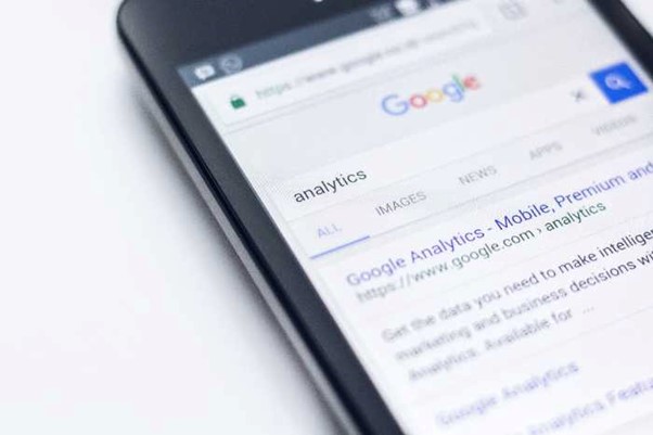 smartphone with opened google search tab, searching text is analytics