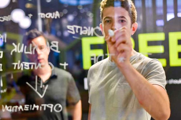 young businessmen writing on glass board during meeting