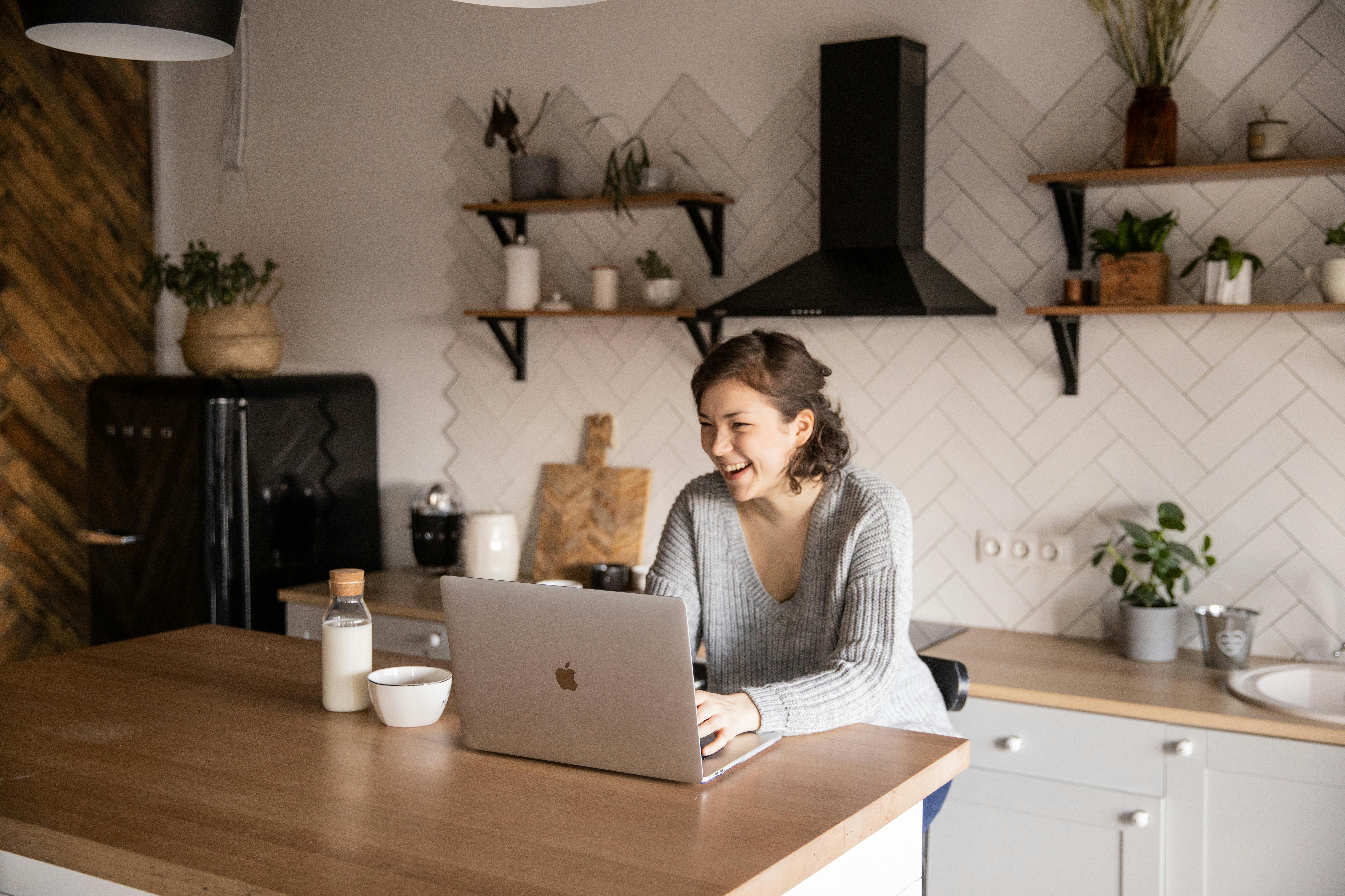 Woman at kitchen with laptop, confident in her course plan