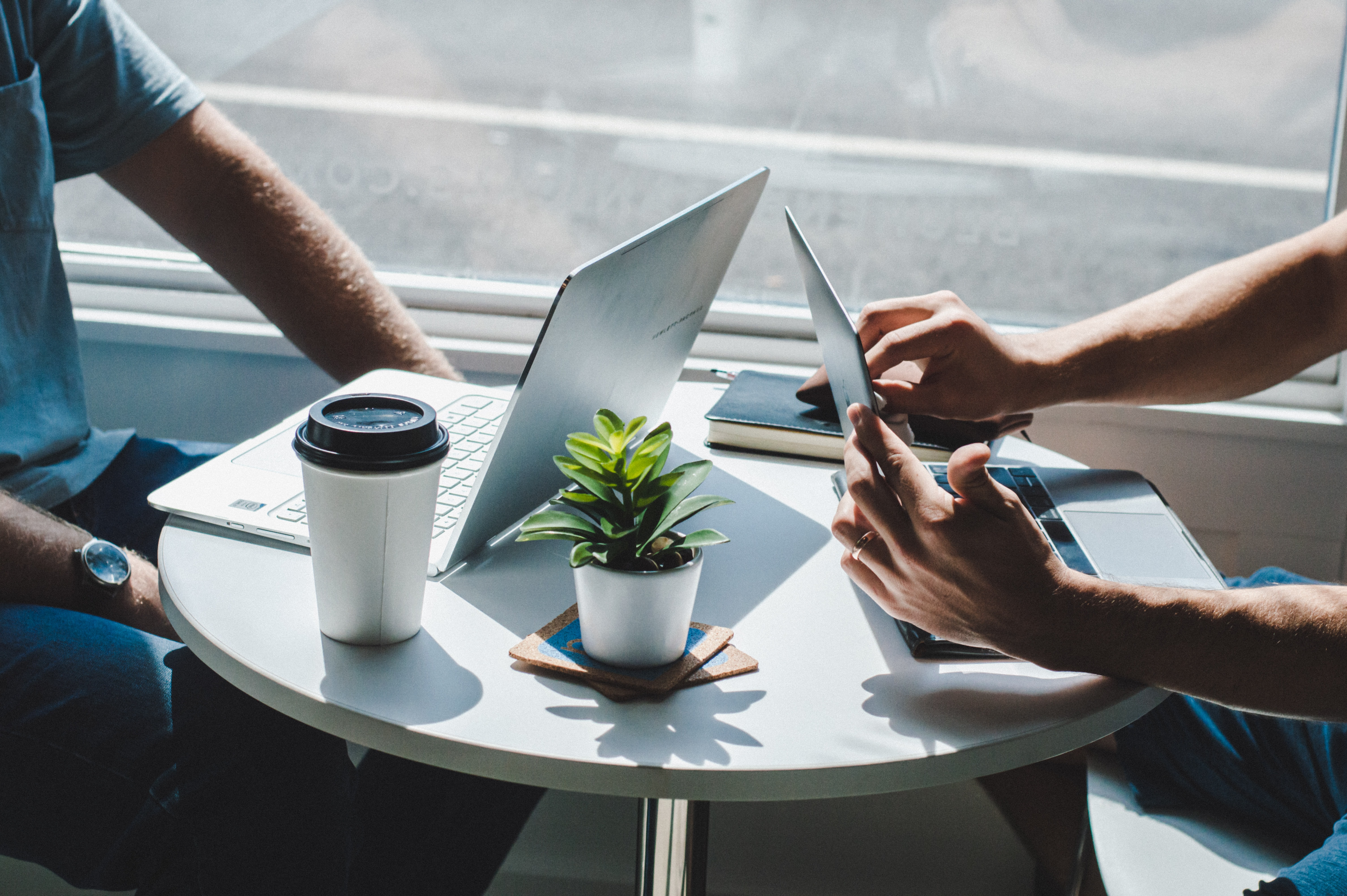 Two people sitting by a table and drinking coffee