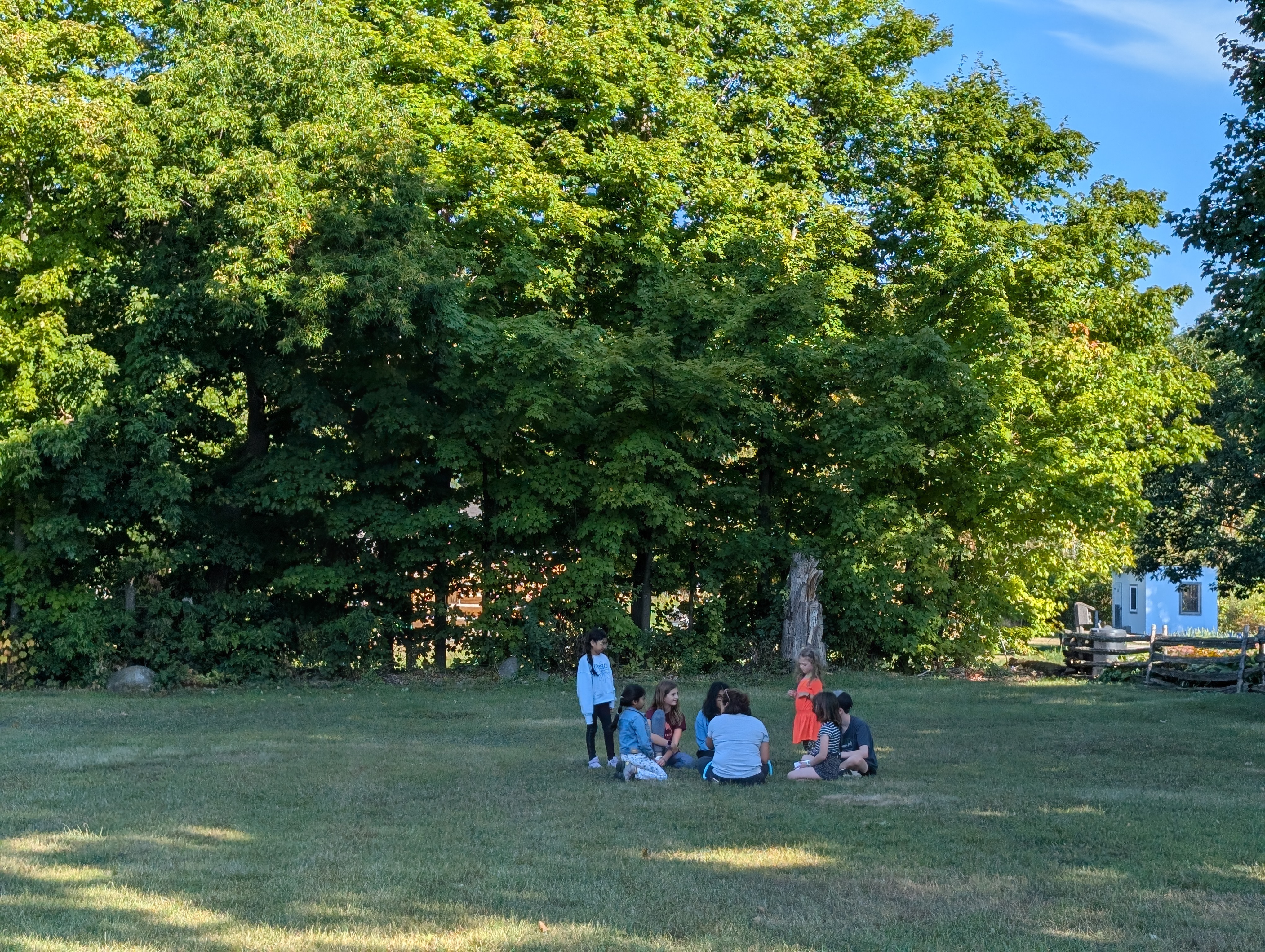 A circle of children outside, having a Socratic discussion.