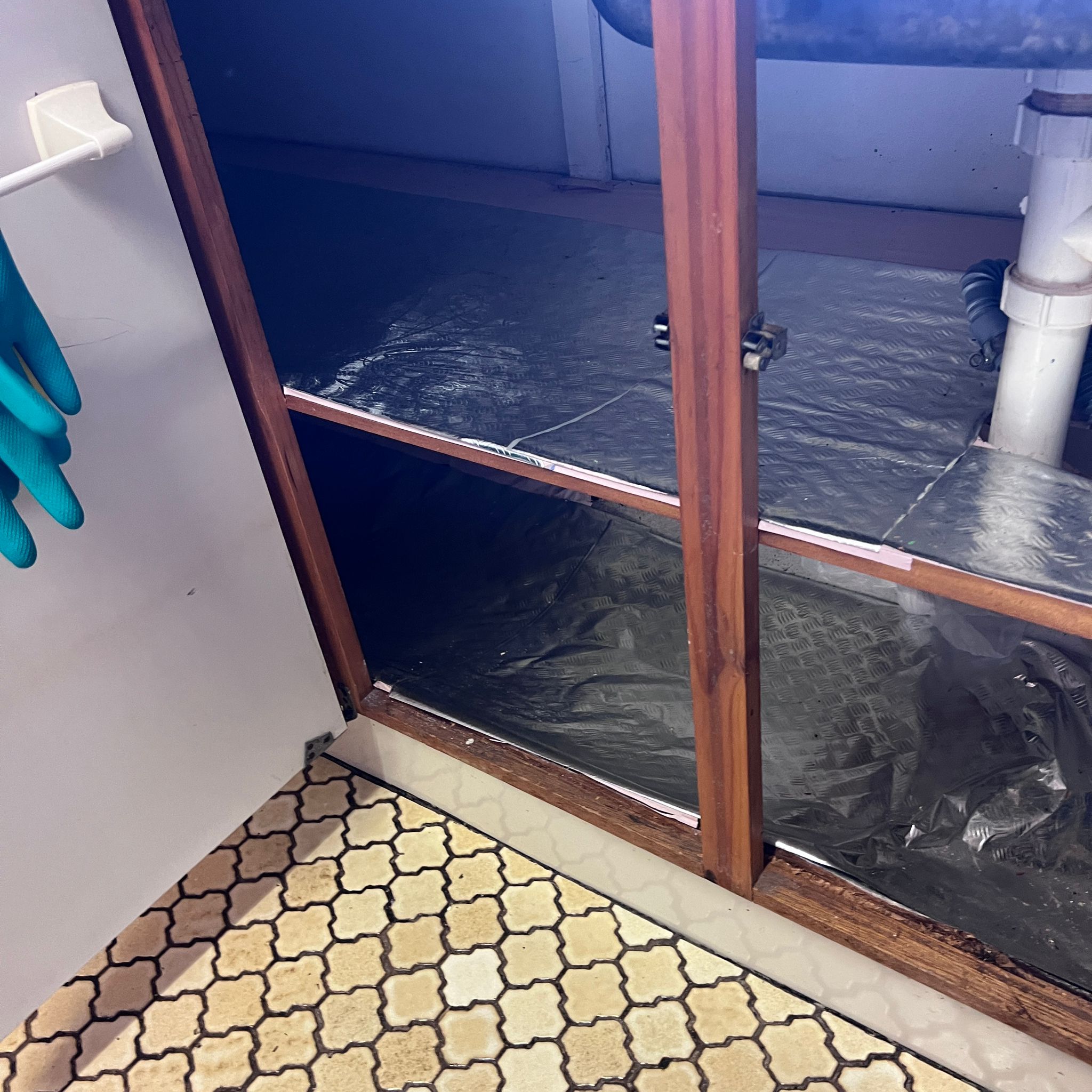 Under-sink kitchen cabinet with damaged shelving visible