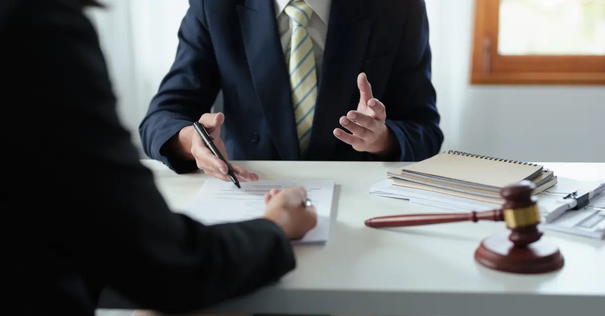 Estate planning attorney discussing legal documents with a client during a consultation, with a gavel and paperwork on the desk.