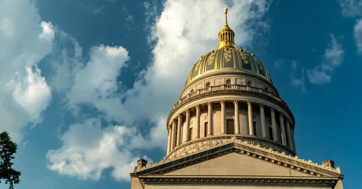 The gold-domed West Virginia State Capitol building against a blue sky with scattered clouds. The gold-domed West Virginia State Capitol building against a blue sky with scattered clouds.