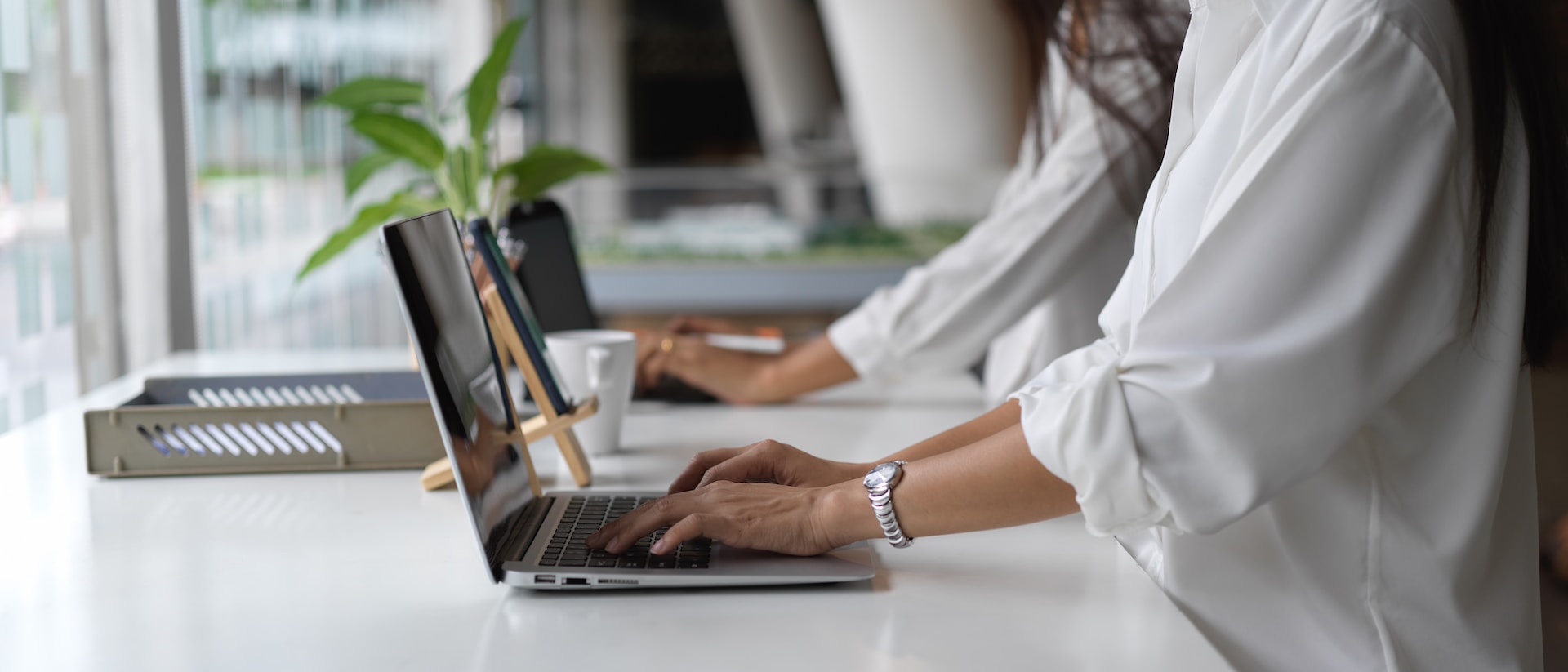 side view of woman typing on laptop in office environment