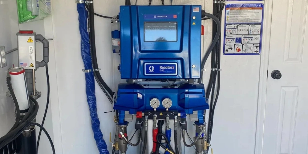 Close-up of spray foam machine control panel and hoses installed inside a custom rig