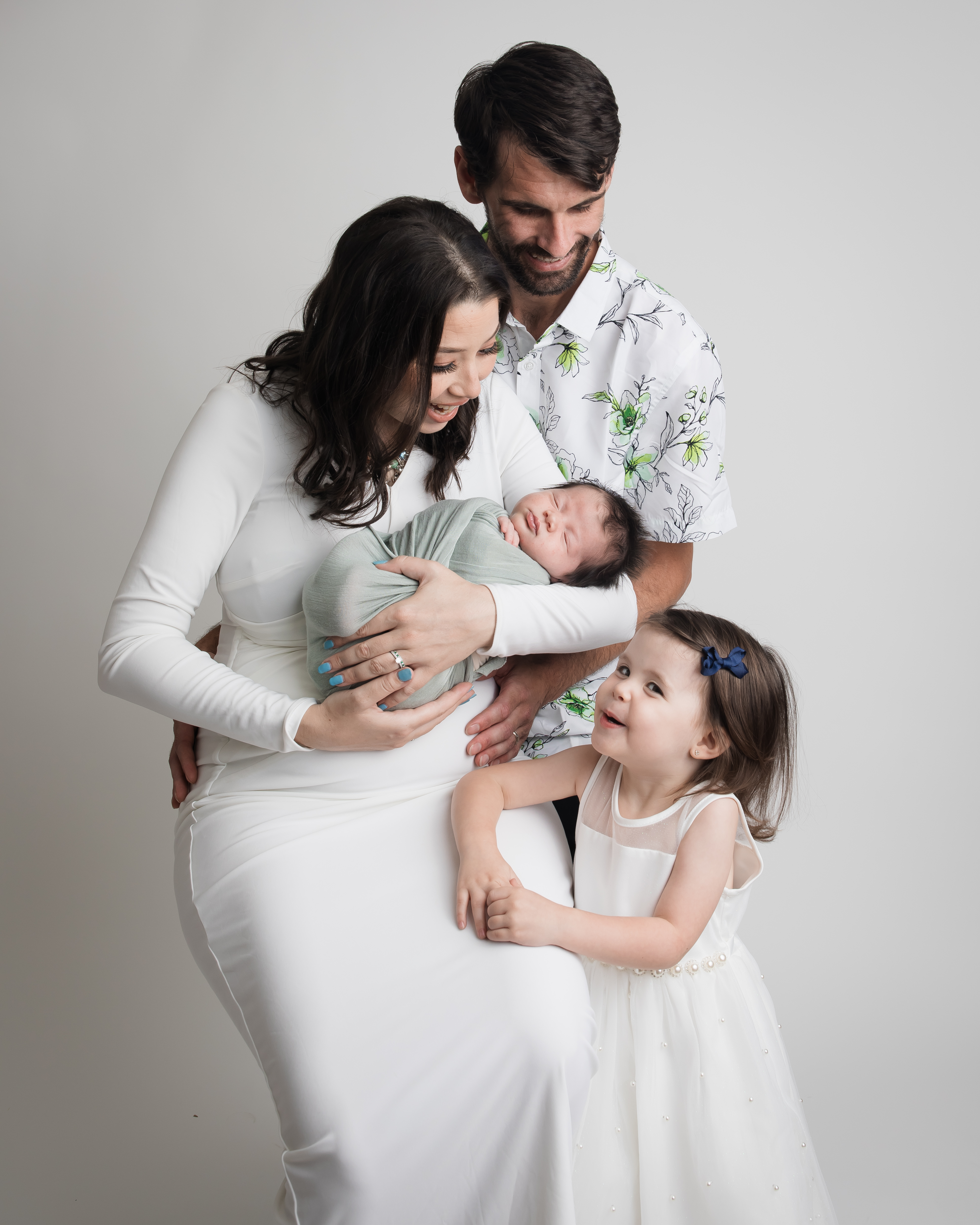 ChatGPT said:  A family shares a joyful moment as the mother holds a swaddled newborn while the father and older sister look on with love. Photographed by Los Angeles photographer Kendra Greenberg Photography.