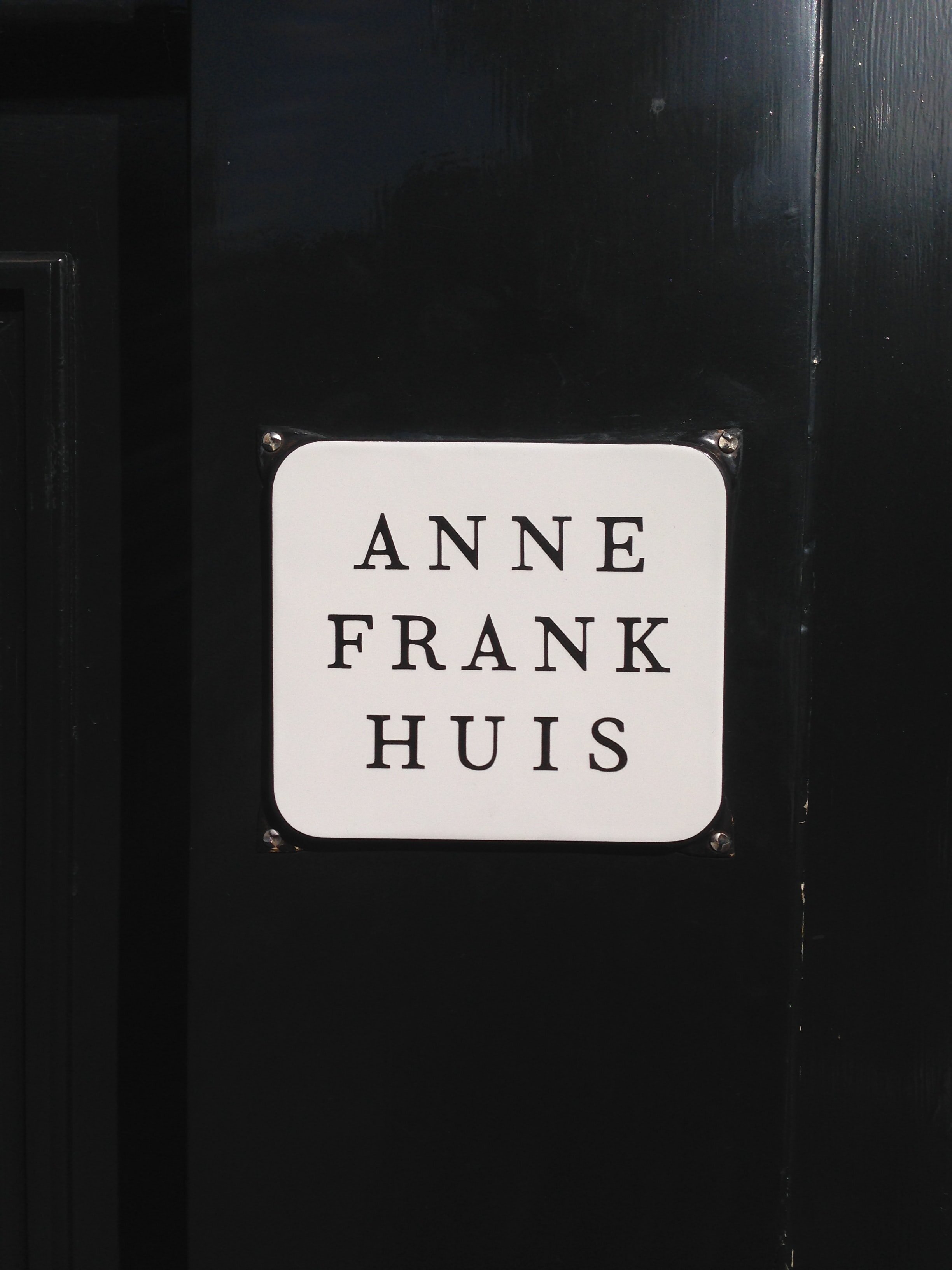 A black door with the sign Anne Frank Hus painted on it. 