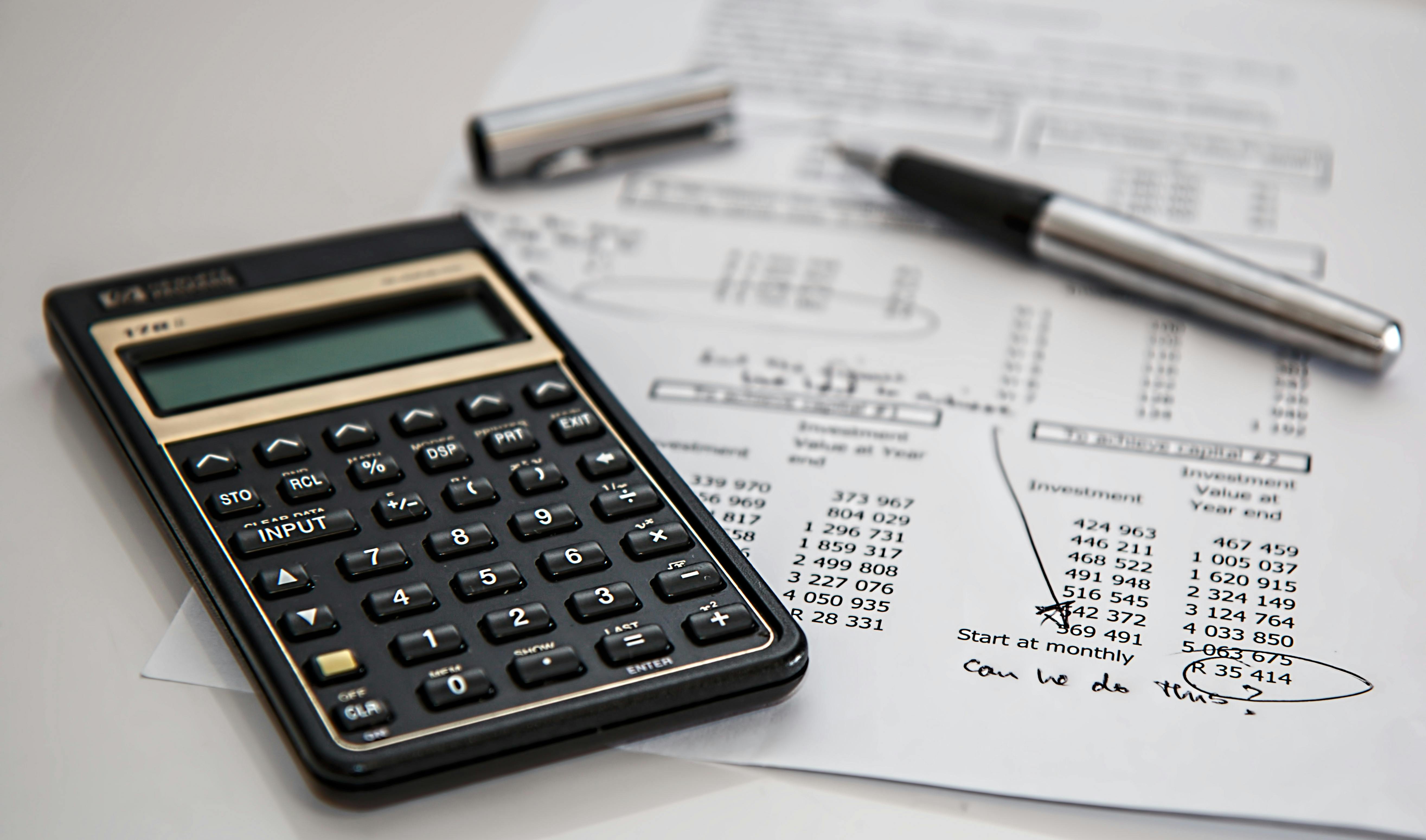 Close-up of a black calculator, financial documents with handwritten notes, and a silver pen on a desk—representing budgeting, accounting, investment planning, or small business financial analysis. Ask ChatGPT Close-up of a black calculator, financial documents with handwritten notes, and a silver pen on a desk—representing budgeting, accounting, investment planning, or small business financial analysis. Ask ChatGPT