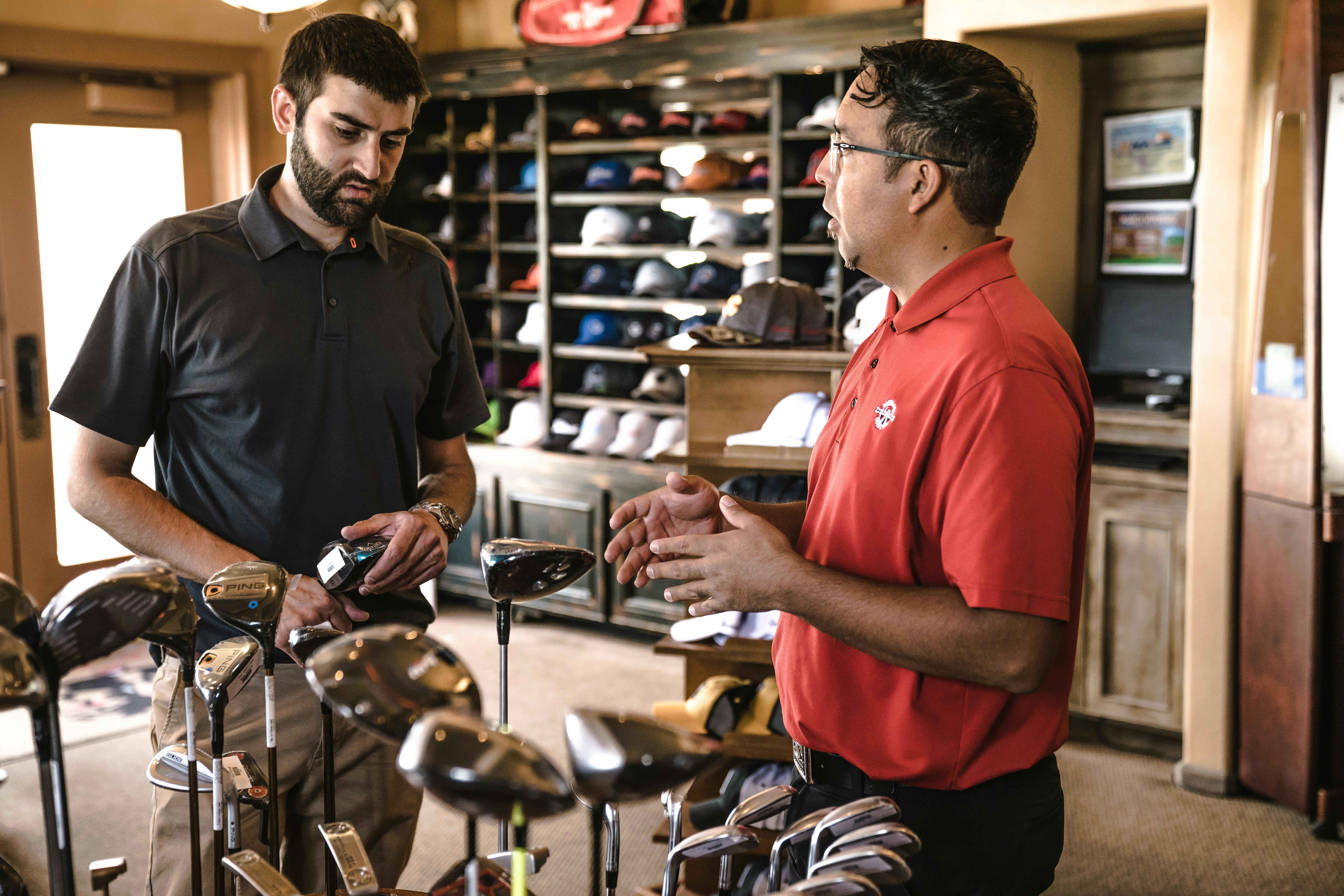 Sales associate assisting a customer in choosing golf clubs at a retail store—engaged product discussion, personalized customer service, and targeted sales experience in a sports equipment setting, showcasing trust-building and audience-focused retail support. Ask ChatGPT Sales associate assisting a customer in choosing golf clubs at a retail store—engaged product discussion, personalized customer service, and targeted sales experience in a sports equipment setting, showcasing trust-building and audience-focused retail support. Ask ChatGPT
