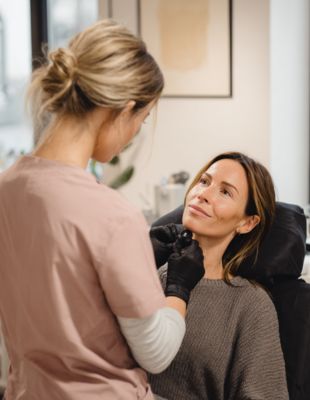 Medical professional consulting with patient before lip filler treatment, emphasising the importance of product transparency, clinical safety, and qualified injectors in aesthetic care. Medical professional consulting with patient before lip filler treatment, emphasising the importance of product transparency, clinical safety, and qualified injectors in aesthetic care.