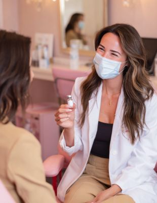 Medical professional at One8Clinic in Melrose Arch, Sandton, wearing a mask and holding wrinkle-relaxing injection vial during a patient consultation for safe, personalised facial rejuvenation treatment.
