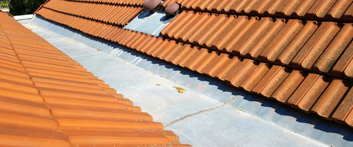 Clean roof valley between terracotta tiles showing proper drainage maintenance