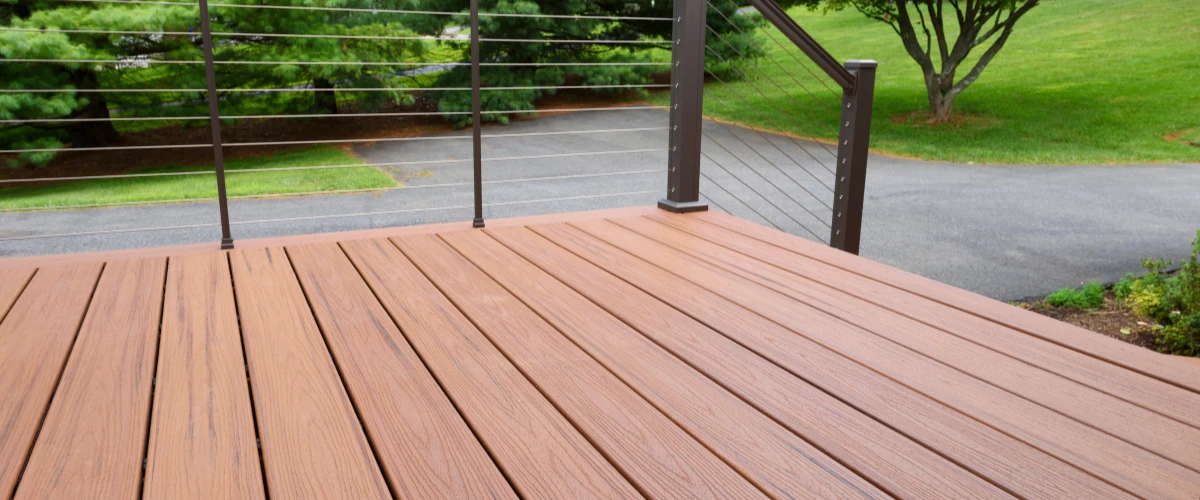 Freshly cleaned and finished wooden deck overlooking yard with modern railing.