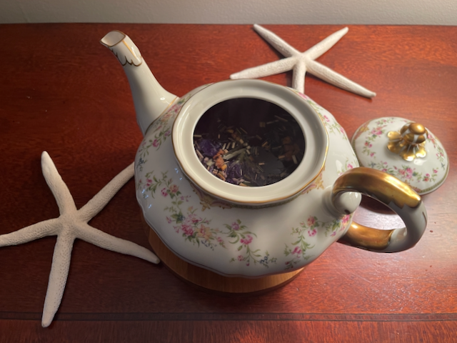 Harney & Sons Fine Teas - Indigo Punch - Brewing in an open teapot with decorative oceanic elements - two starfish on each side of the teapot. Harney & Sons Fine Teas - Indigo Punch - Brewing in an open teapot with decorative oceanic elements - two starfish on each side of the teapot.