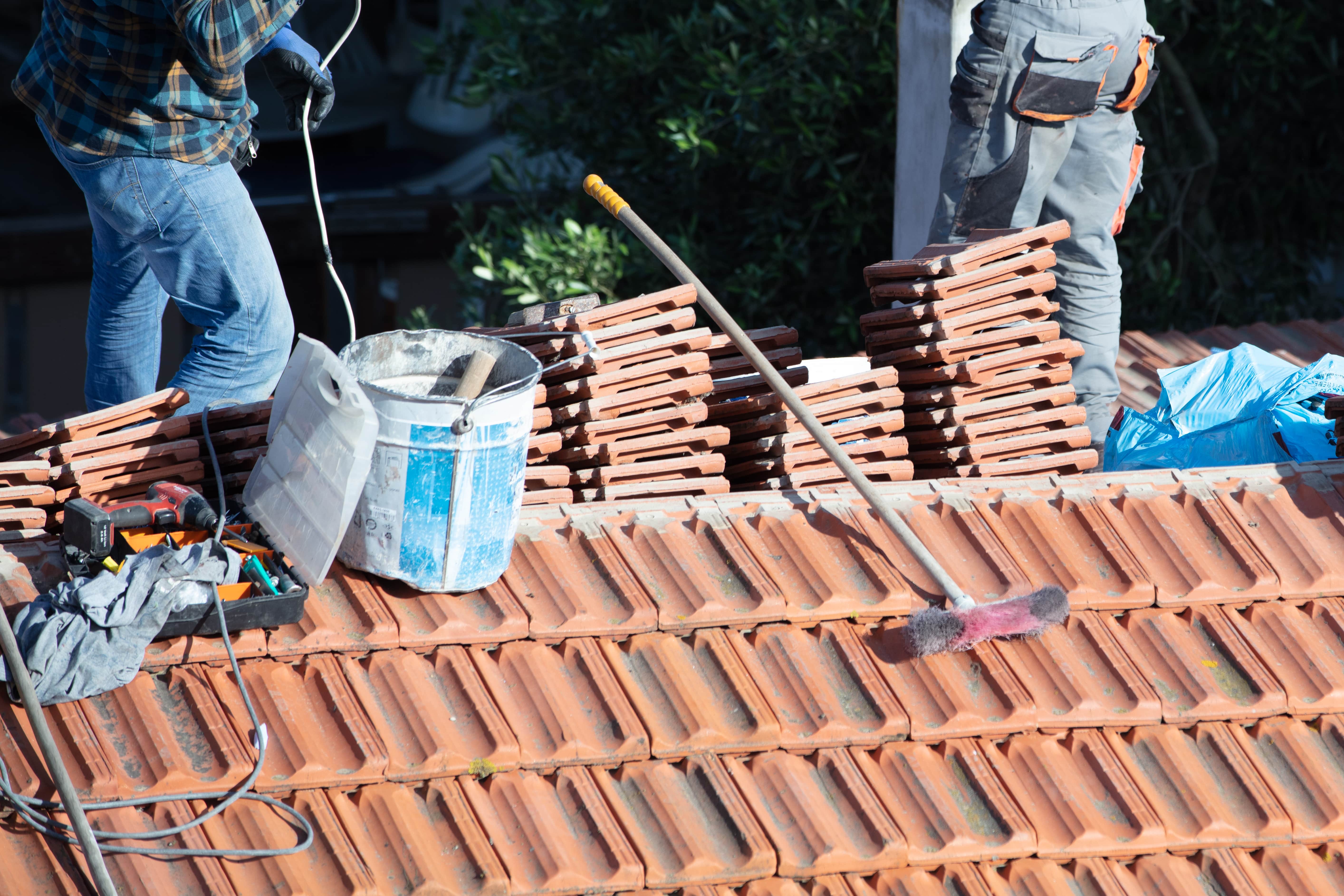 expert roofer repairing red roof tiles