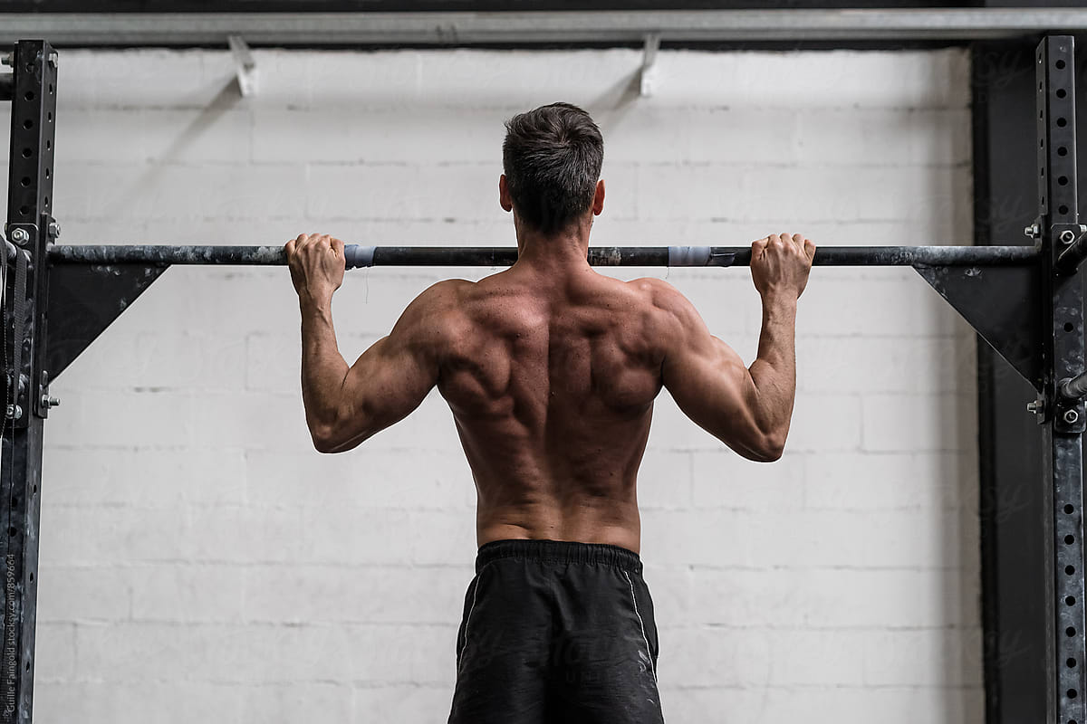 Image of man doing pull-ups showing his back muscles as he approaches the top of the rep with perfect form.