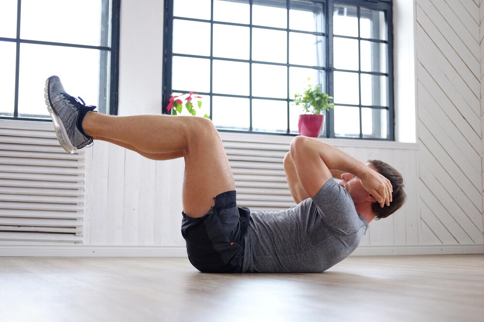 Man conducting an abs workout at home with legs elevated in a crunch position on the floor.