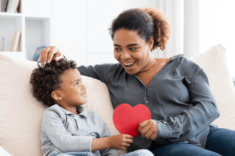 Mother and small boy on bed holding a heart