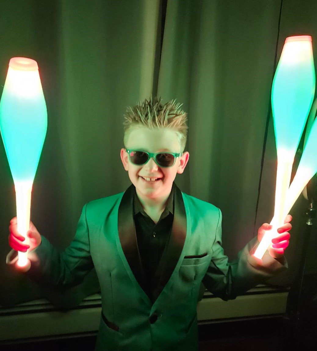 A 9-year old juggler in glow in the dark torch wearing green suit A 9-year old juggler in glow in the dark torch wearing green suit