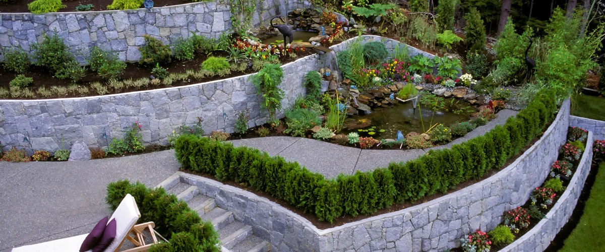 Tiered stone garden with curved retaining walls and water feature Tiered stone garden with curved retaining walls and water feature
