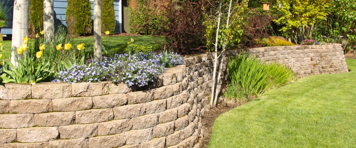 Decorative retaining wall with colorful flowerbed in residential garden Decorative retaining wall with colorful flowerbed in residential garden