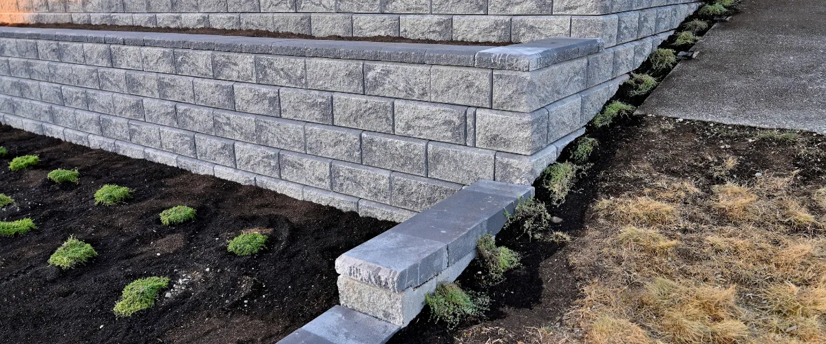 Modern concrete retaining wall installation with newly planted greenery Modern concrete retaining wall installation with newly planted greenery