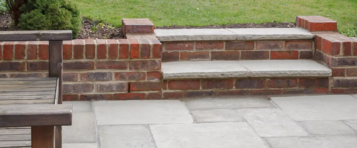 Brick retaining wall with stone steps in a backyard patio