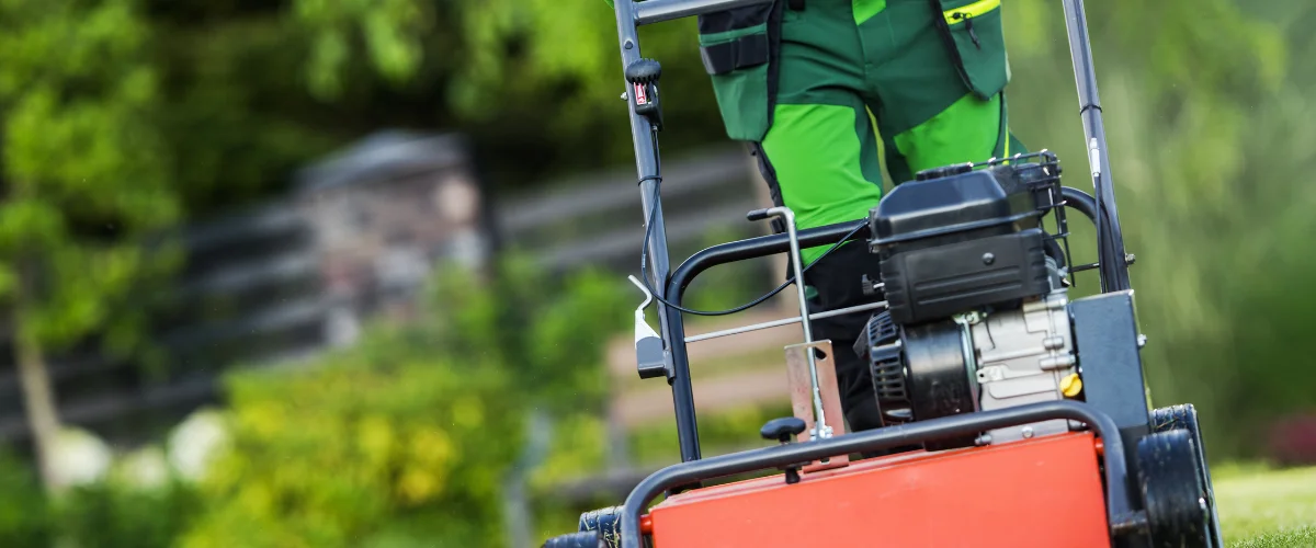 Landscaper mowing grass with professional lawn care equipment.