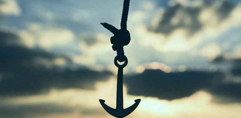 A silhouette of an anchor hanging from a rope against a dramatic sky with clouds and sunlight filtering through, symbolizing stability and grounding A silhouette of an anchor hanging from a rope against a dramatic sky with clouds and sunlight filtering through, symbolizing stability and grounding