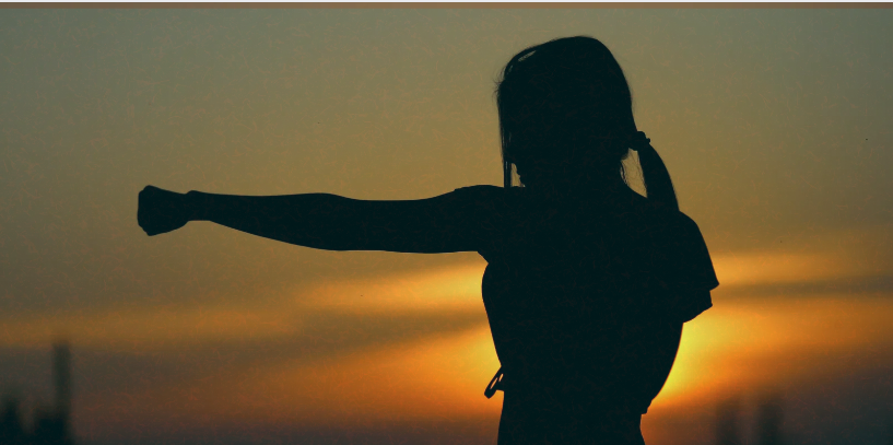 A silhouette of a woman in a fighting stance with her arm extended, set against a golden sunset, representing strength, determination, and resilience A silhouette of a woman in a fighting stance with her arm extended, set against a golden sunset, representing strength, determination, and resilience