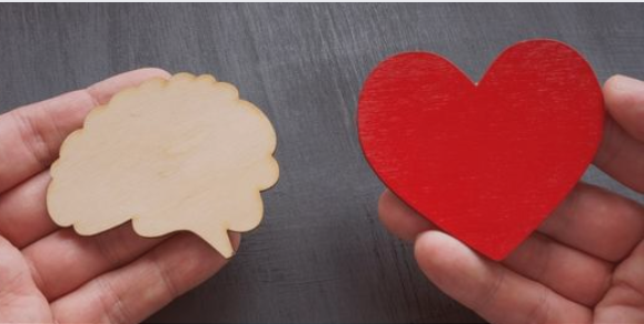 A pair of hands holding two wooden cutouts – one in the shape of a brain and the other a red heart. The image symbolizes the balance between logic and emotions, decision-making, or emotional intelligence A pair of hands holding two wooden cutouts – one in the shape of a brain and the other a red heart. The image symbolizes the balance between logic and emotions, decision-making, or emotional intelligence