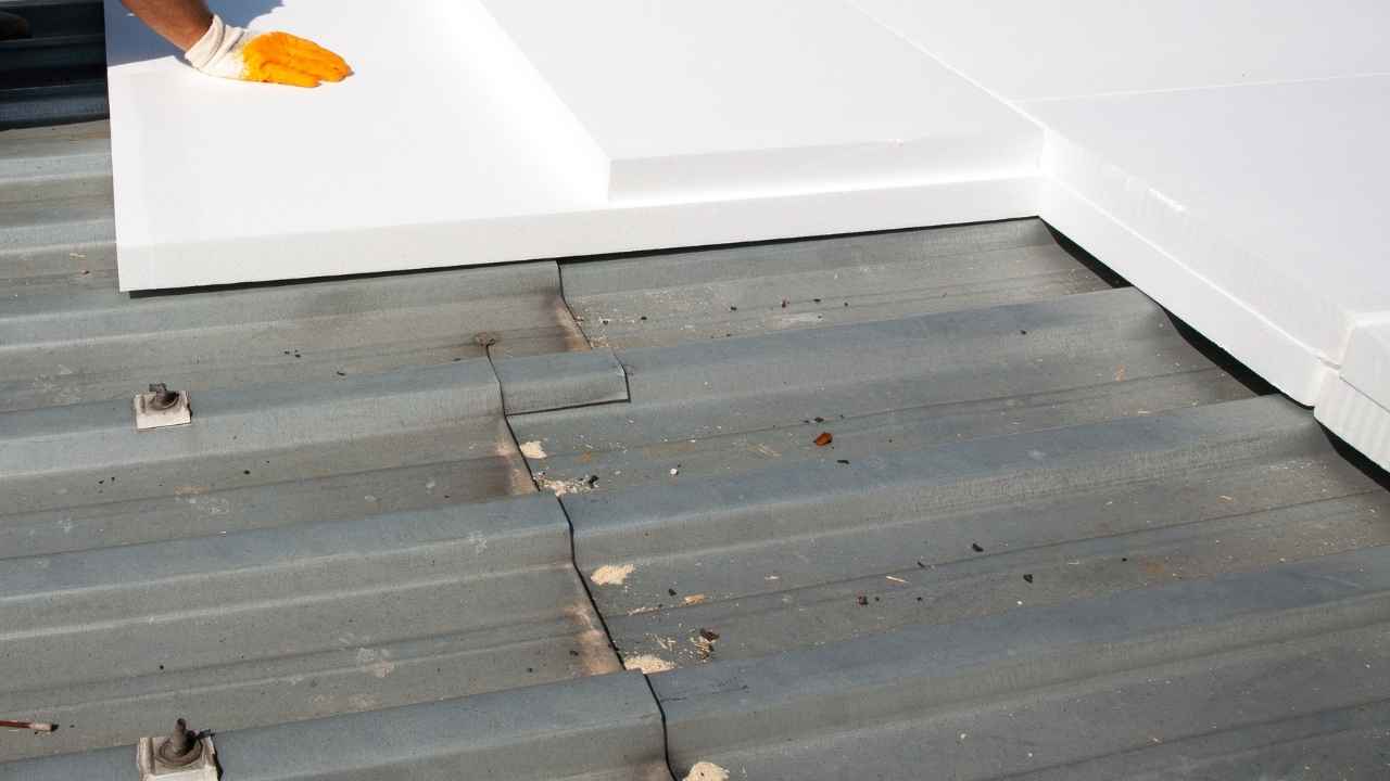 Close-up of a roofer placing insulation panels on a metal roof, wearing gloves for proper handling. Close-up of a roofer placing insulation panels on a metal roof, wearing gloves for proper handling.