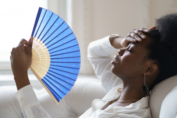 woman grimaces in discomfort amidst high indoor heat woman grimaces in discomfort amidst high indoor heat