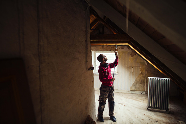 man inspects attic for wear or damage man inspects attic for wear or damage