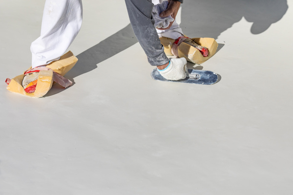 a worker applies polyurethane roof coatings, creating a protective barrier against weathering a worker applies polyurethane roof coatings, creating a protective barrier against weathering