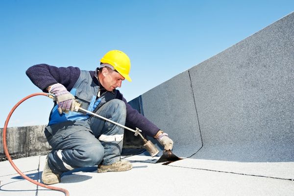 Roofer applying heat to seal a flat roof, showcasing repair techniques for hail-damaged roofing systems. Roofer applying heat to seal a flat roof, showcasing repair techniques for hail-damaged roofing systems.