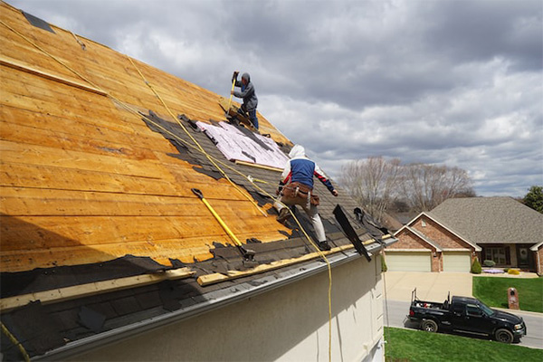 Roofers replacing shingles on a steep residential roof, emphasizing the process of deciding between repair, patching, or full replacement. Roofers replacing shingles on a steep residential roof, emphasizing the process of deciding between repair, patching, or full replacement.