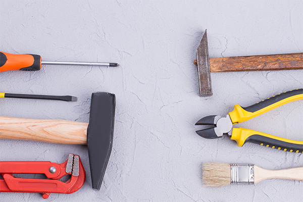 Assorted tools laid out on a surface, symbolizing the choice between DIY roof replacement and hiring professional roofers. Assorted tools laid out on a surface, symbolizing the choice between DIY roof replacement and hiring professional roofers.