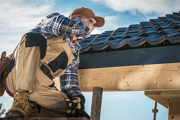 Roofer inspecting a tiled roof under clear skies, emphasizing preparation and maintenance for winter weather conditions. Roofer inspecting a tiled roof under clear skies, emphasizing preparation and maintenance for winter weather conditions.