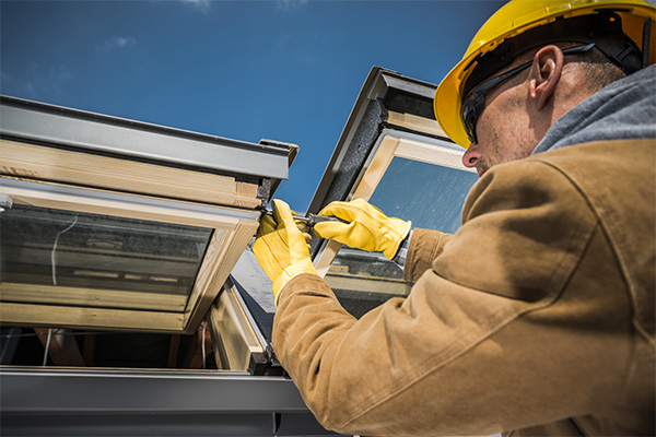 Worker repairing a skylight on a roof, emphasizing the importance of proper installation and maintenance for energy efficiency and leak prevention. Worker repairing a skylight on a roof, emphasizing the importance of proper installation and maintenance for energy efficiency and leak prevention.