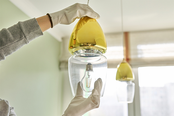Person installing a pendant light fixture, emphasizing safety and precision in hanging lights efficiently. Person installing a pendant light fixture, emphasizing safety and precision in hanging lights efficiently.