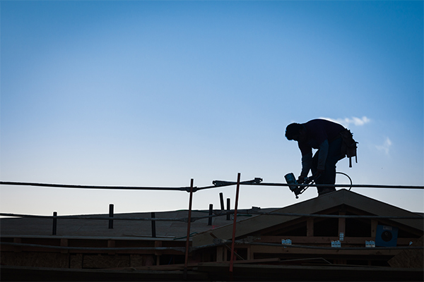 Silhouette of a roofing contractor working on a rooftop at sunset, highlighting the risks and dangers of roofing jobs. Silhouette of a roofing contractor working on a rooftop at sunset, highlighting the risks and dangers of roofing jobs.