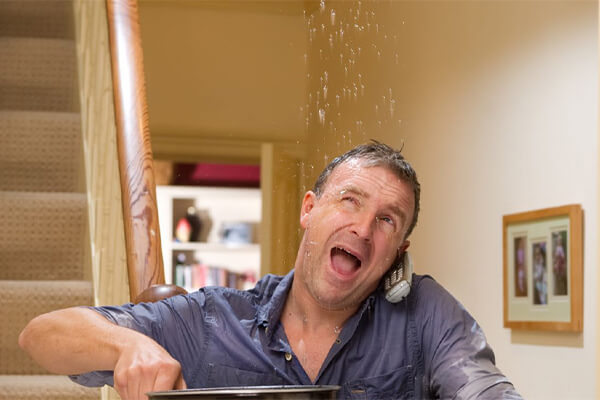 Frustrated homeowner catching water in a bucket from a leaking ceiling, highlighting the need for regular roof inspections and timely repairs. Frustrated homeowner catching water in a bucket from a leaking ceiling, highlighting the need for regular roof inspections and timely repairs.