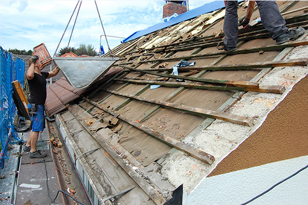 A roofing team removing old roofing materials, clearing the surface for a fresh installation with safety precautions in place. A roofing team removing old roofing materials, clearing the surface for a fresh installation with safety precautions in place.