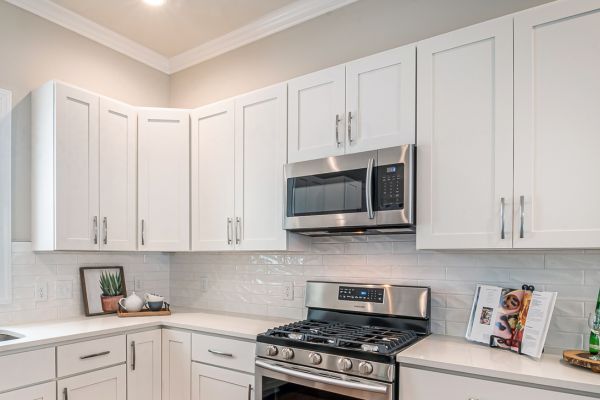 Modern kitchen with white shaker cabinets, stainless steel appliances, subway tile backsplash, and quartz countertops Modern kitchen with white shaker cabinets, stainless steel appliances, subway tile backsplash, and quartz countertops