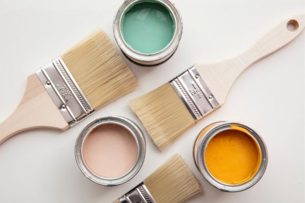 Paintbrushes and open paint cans with pastel and vibrant colors on a white background Paintbrushes and open paint cans with pastel and vibrant colors on a white background