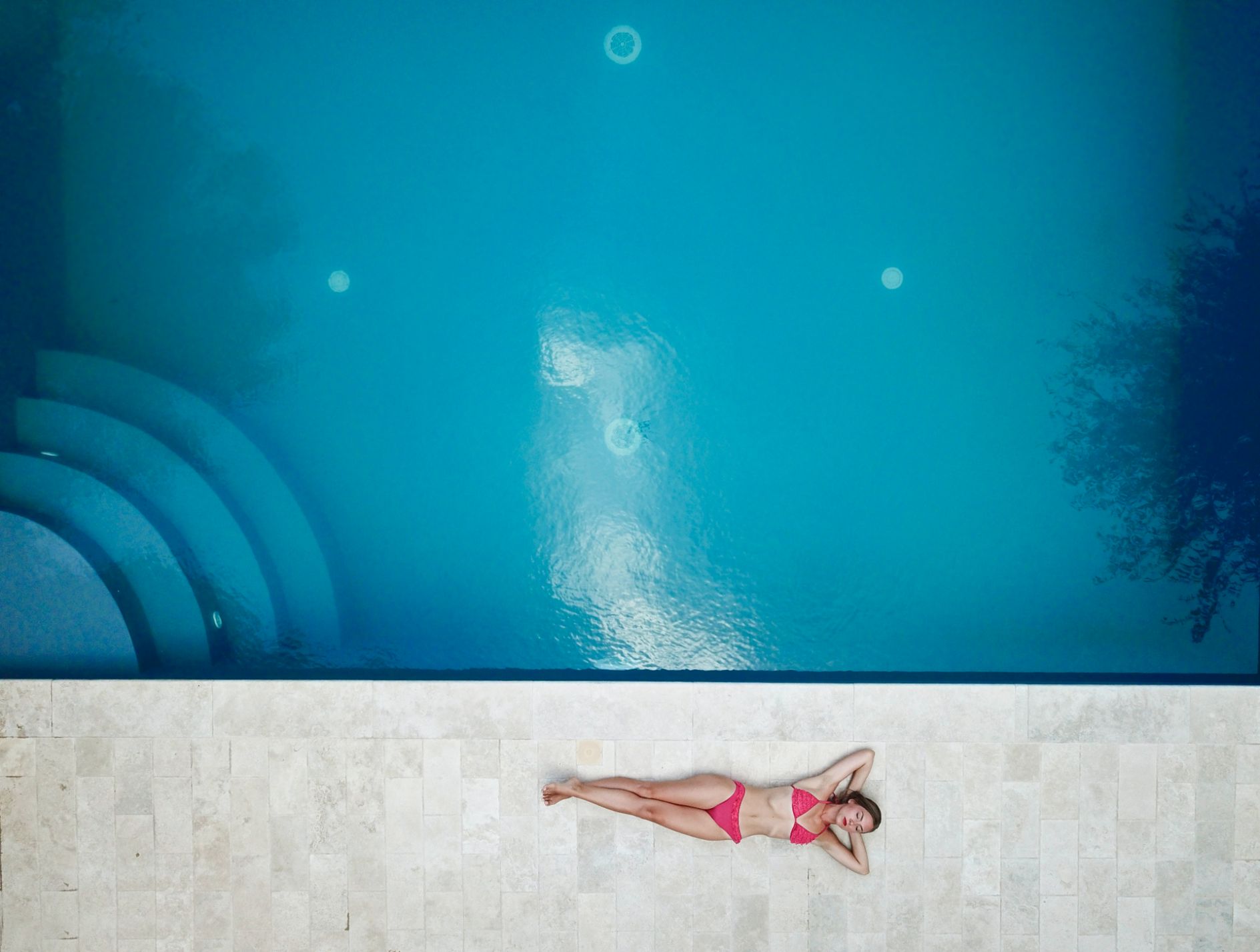 Woman laying next to pool from top view