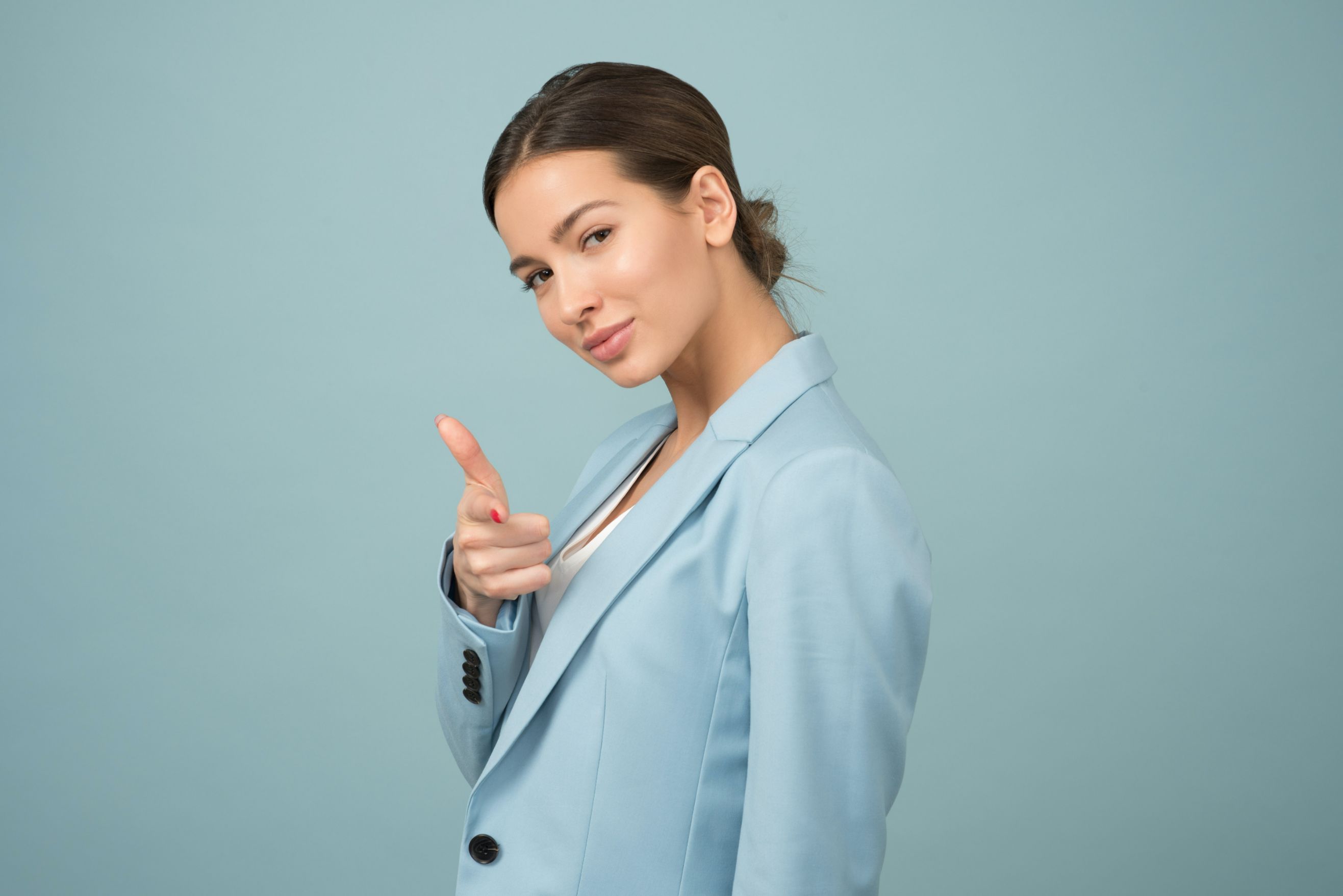 Woman in sports coat pointing a finger at the camera